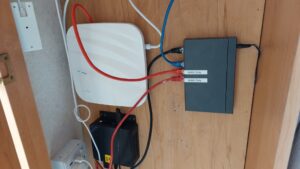 Photo showing gl inet router, switch and beelink mini PC in a cupboard